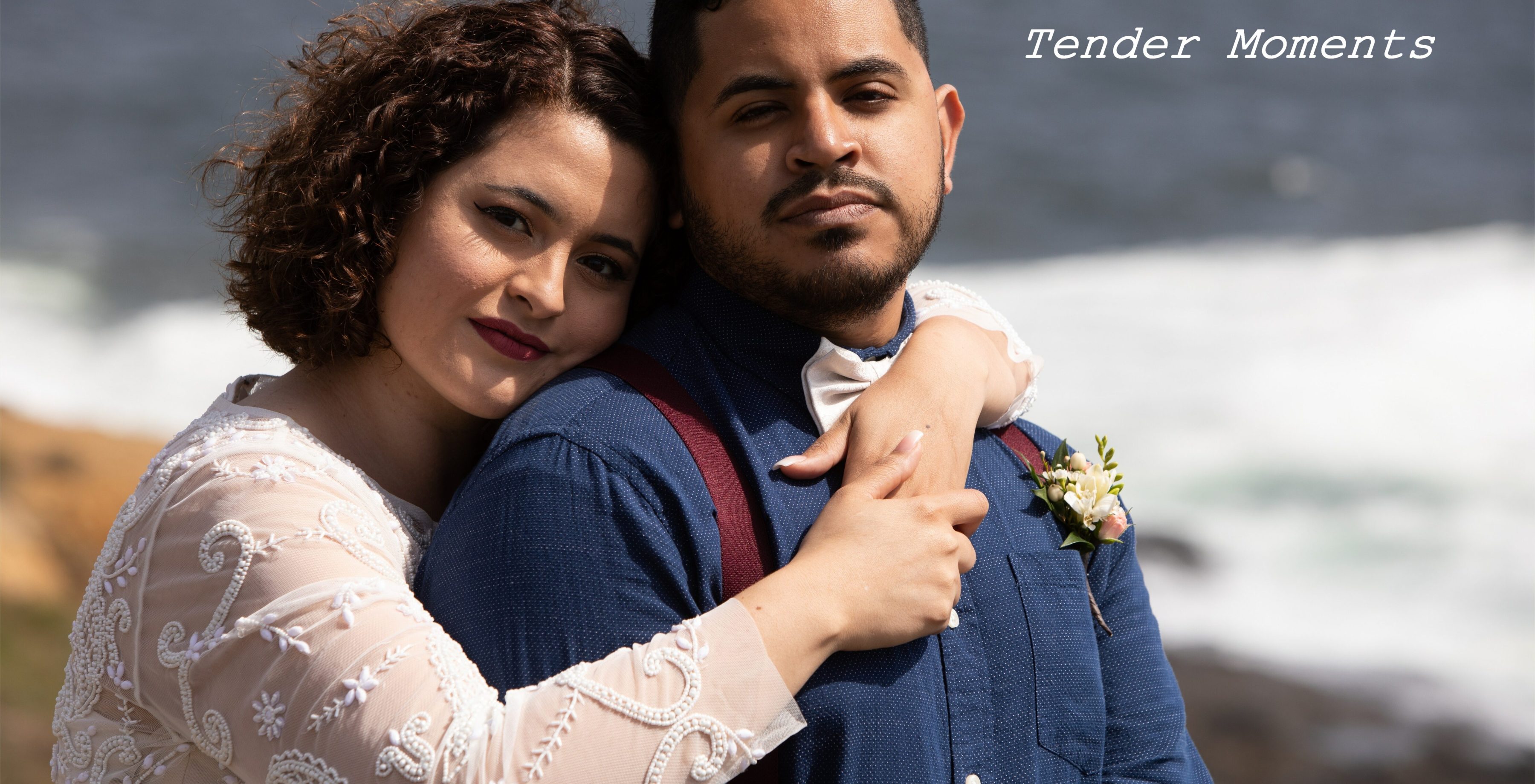Wedding couple embracing by ocean shoreline